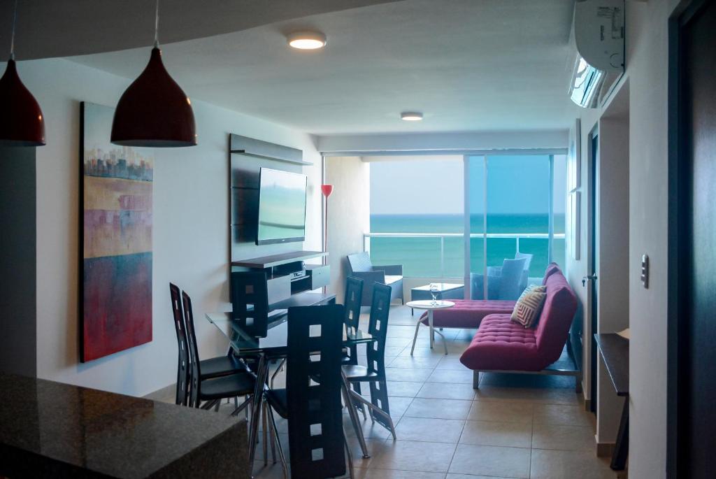 sala de estar con mesa, sillas y TV en Lindo Departamento al pie de playa Edificio TORRE OCEÁNICA, en Salinas