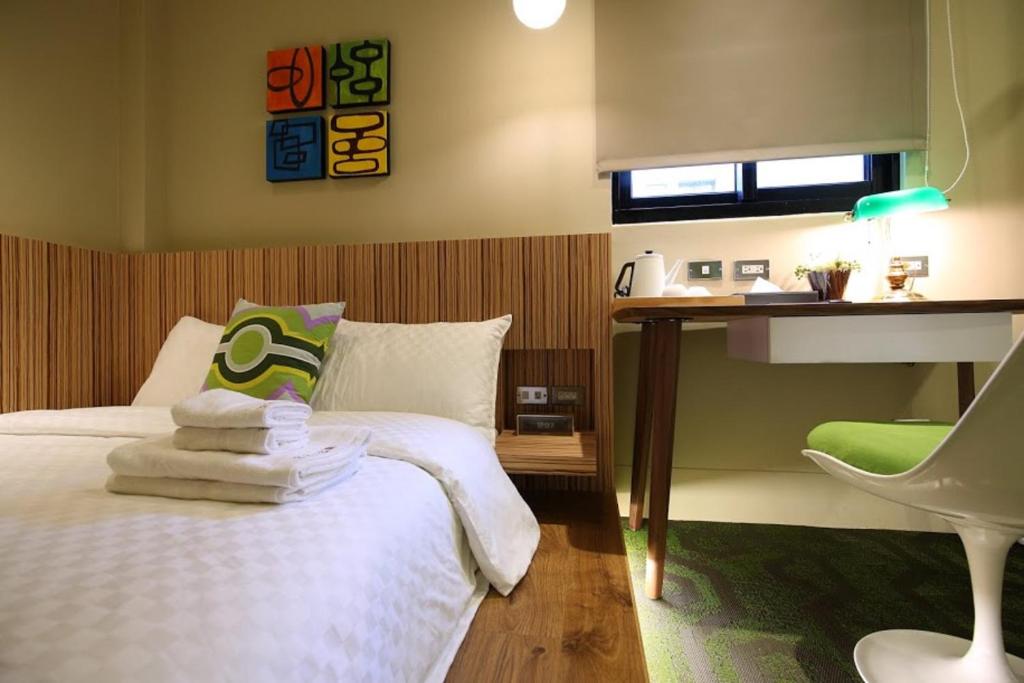 a bedroom with a bed with a desk and a chair at 321 Apartment B&amp;B in Hualien City