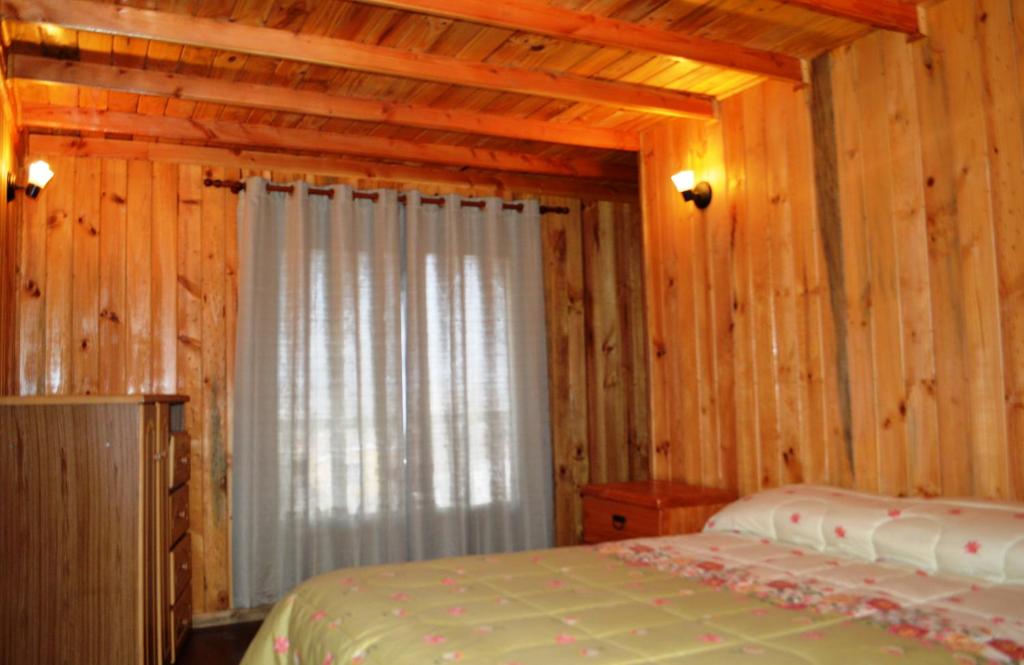 a bedroom with a bed in a log cabin at Hostal Doña Tamy in Quintero