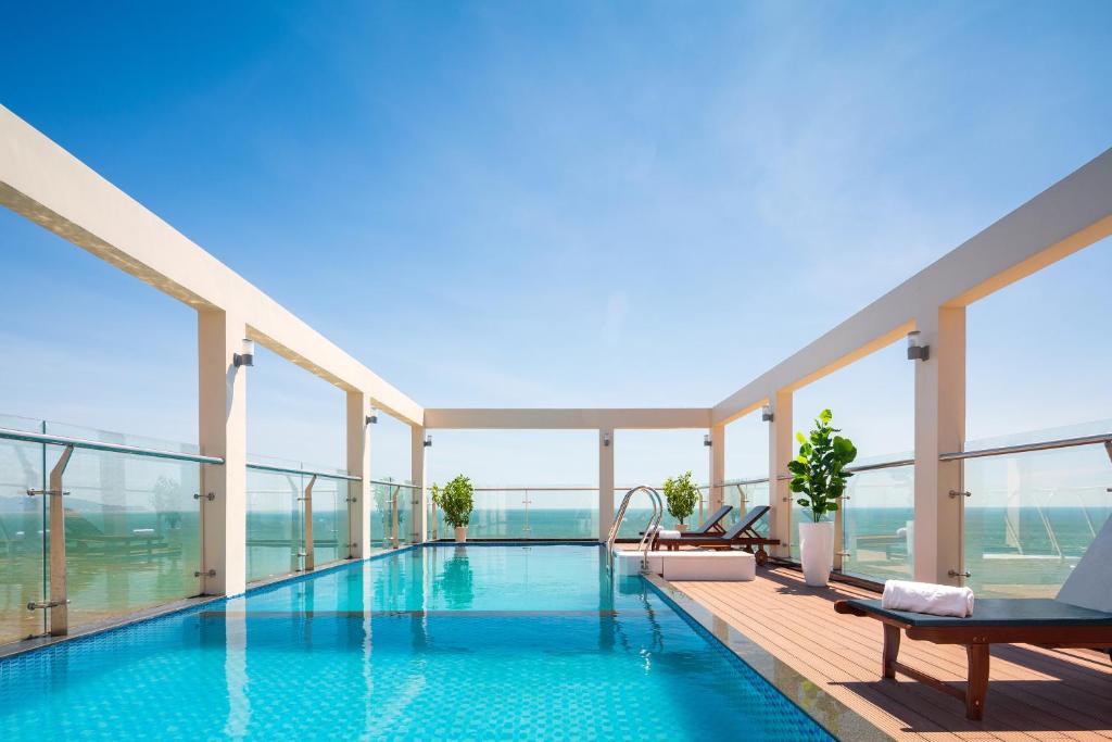 a hotel swimming pool with a view of the ocean at Nolis Hotel in Vung Tau