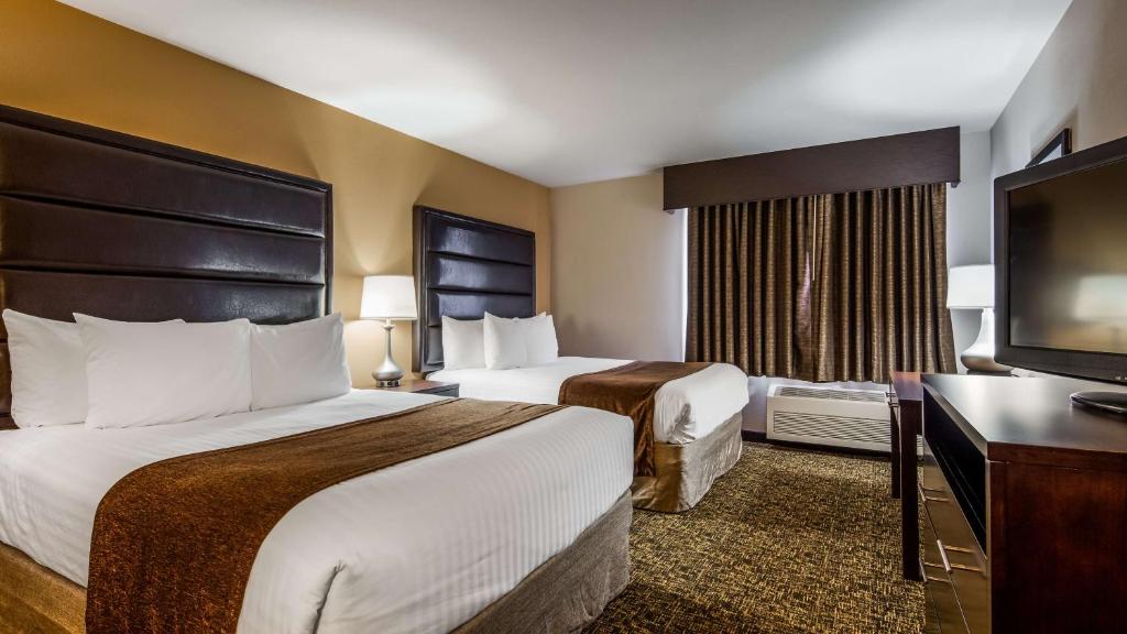 a hotel room with two beds and a flat screen tv at Best Western Oak Meadows Inn in Saint Helens