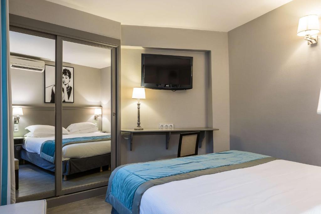 a hotel room with two beds and a mirror at Best Western Montcalm in Paris
