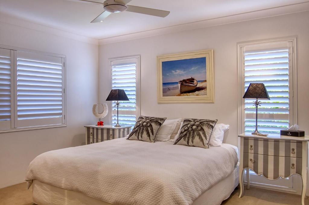 a white bedroom with a bed and two windows at Cronulla Beach House B&B in Cronulla