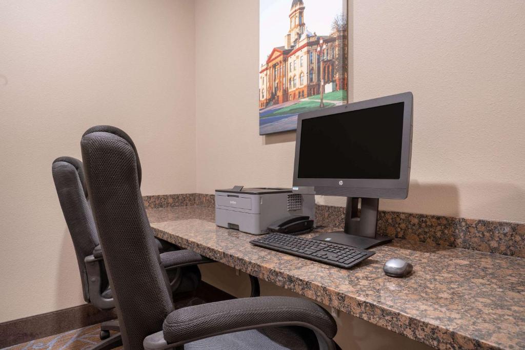 an office with a desk with a computer and two chairs at AmericInn by Wyndham Windom in Windom