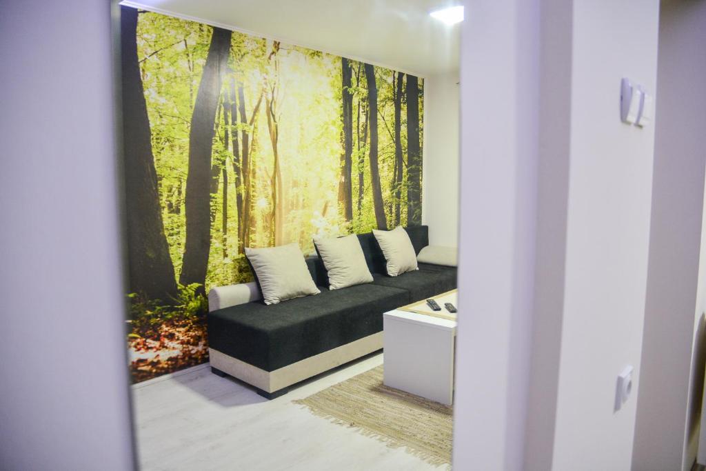 - un salon avec un canapé orné d'une fresque murale représentant la forêt dans l'établissement Allegro dream, à Vranje