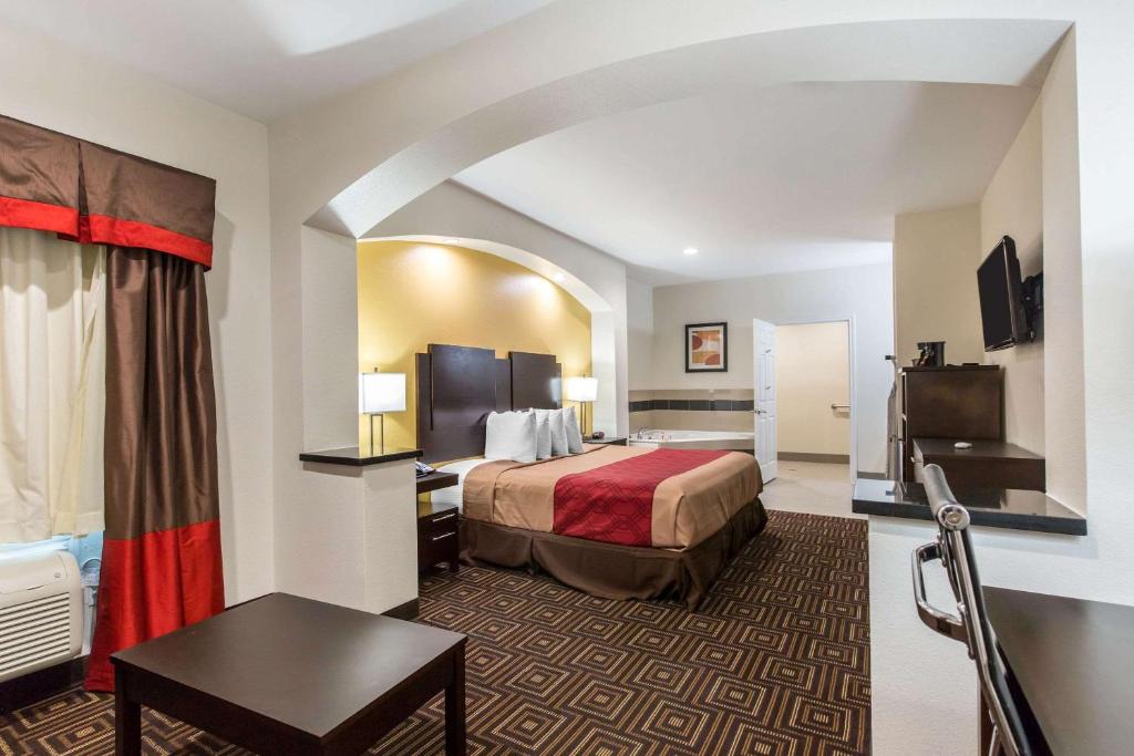 a hotel room with a bed and a table at Scottish Inns & Suites Spring - Houston North in Spring
