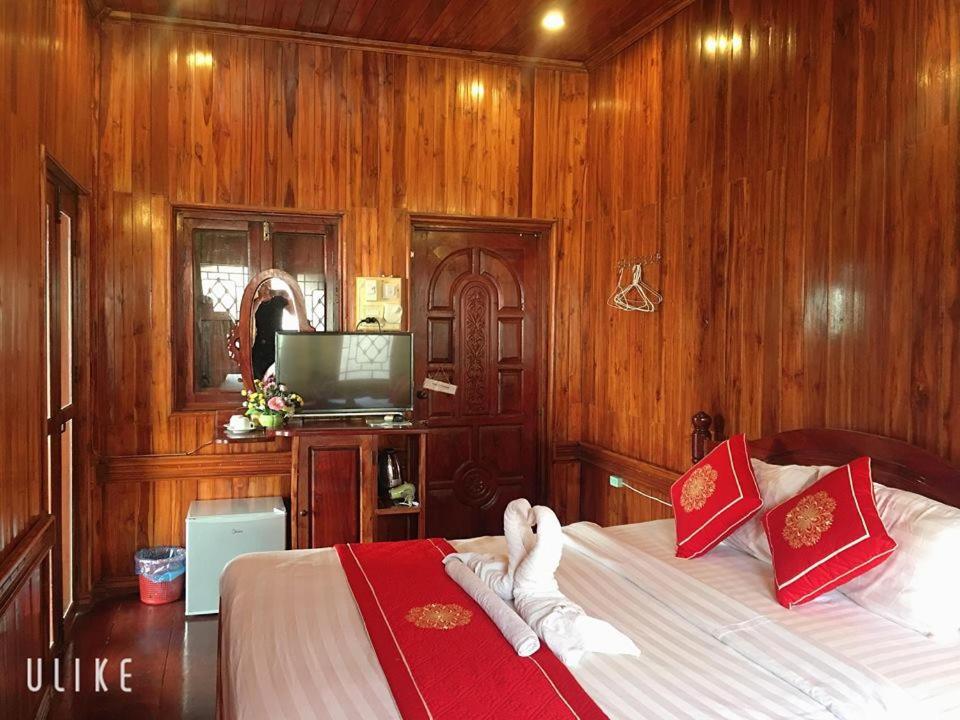 a bedroom with a bed with wooden walls and a tv at Soutikone Place House 2 in Luang Prabang