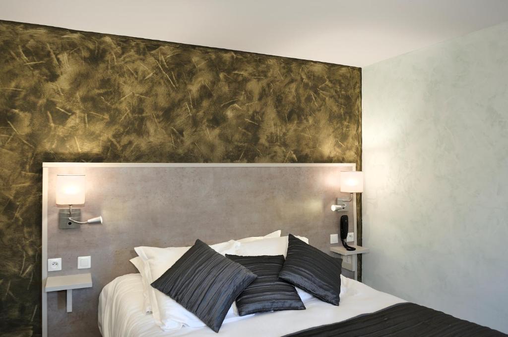 1 cama con almohadas blancas y negras en un dormitorio en Logis Auberge À La Tête De Lard, en La Ferté-Imbault