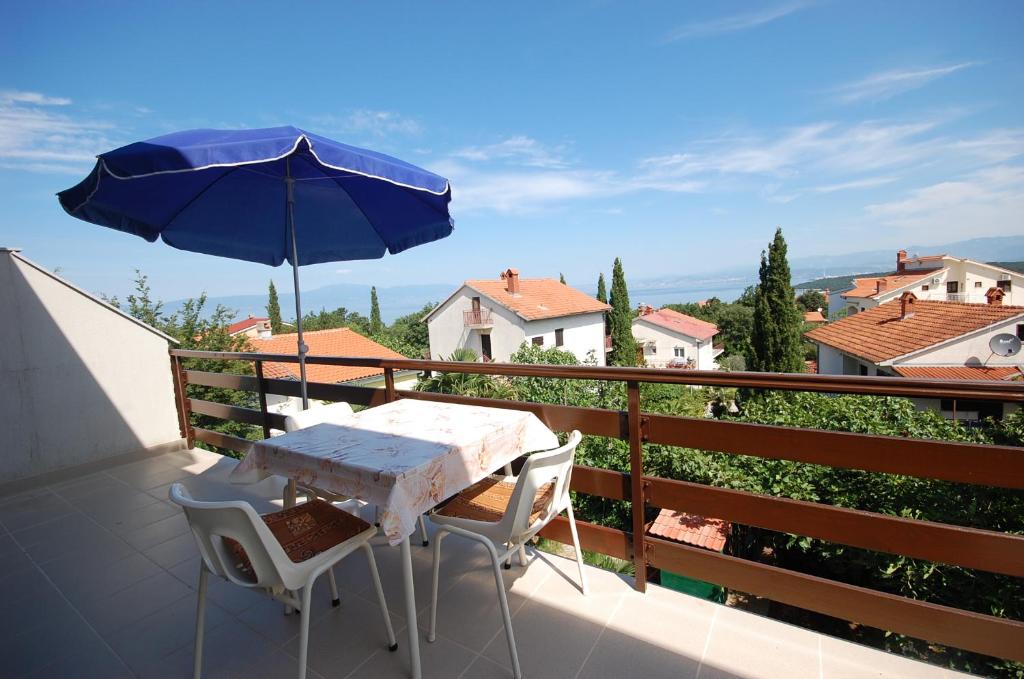 una mesa y sillas en un balcón con sombrilla en Apartments Filosevic, en Njivice