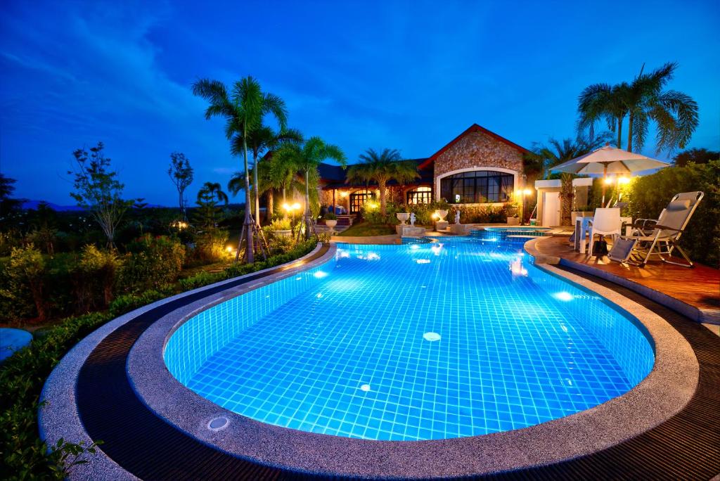a swimming pool in front of a house at night at Chateau de Prim Khao Yai in Ban Sap Phlu