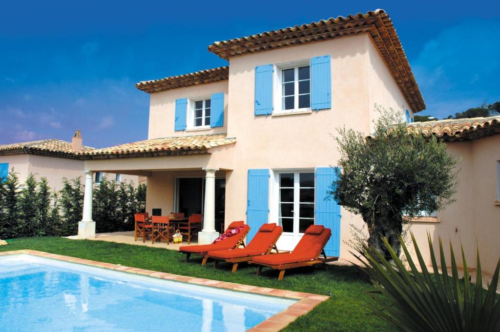 une villa avec une piscine en face d'une maison dans l'établissement Lagrange Vacances Carré Beauchêne, à Sainte-Maxime