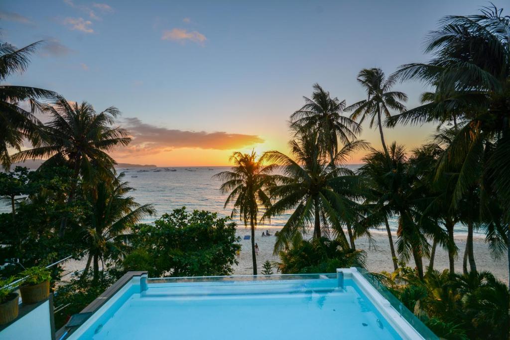 uma piscina com vista para o oceano e palmeiras em Signature Boracay formerly La Banca House em Boracay