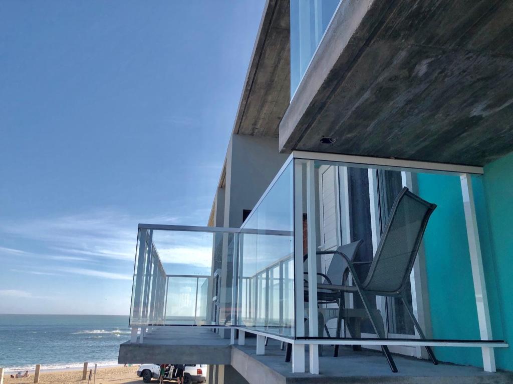 Casa con balcón con silla en la playa en Las Olas Aparts, en La Paloma
