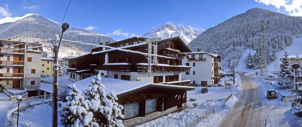 un lodge de ski dans les montagnes avec de la neige au sol dans l'établissement Hotel Mignon, à Ponte di Legno
