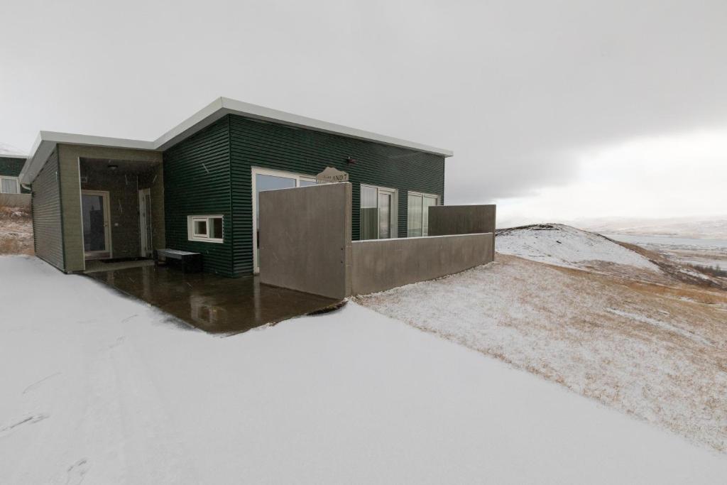 una casa verde in cima a una collina innevata di Hrimland Cottages ad Akureyri