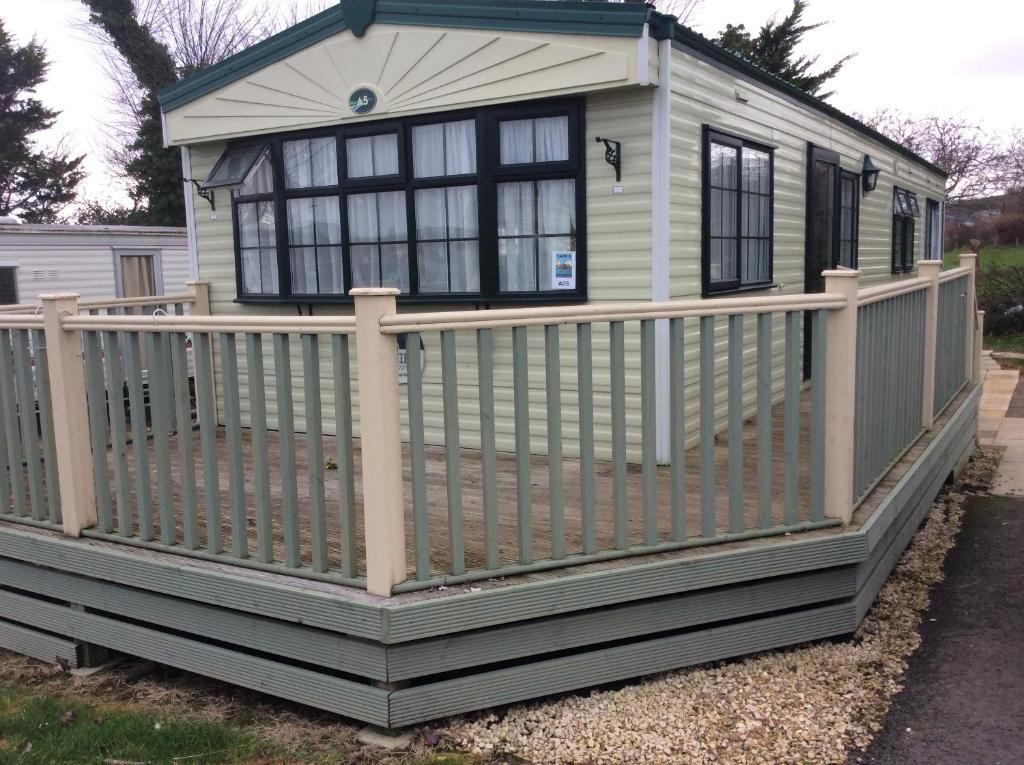 a small house with a fence on a porch at Tarka holiday park, 5A in Barnstaple