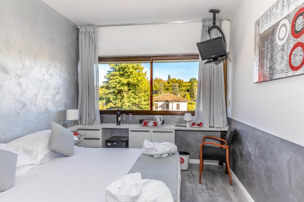 a room with two beds and a desk and a sink at Hotel Valpolicella International in San Pietro in Cariano