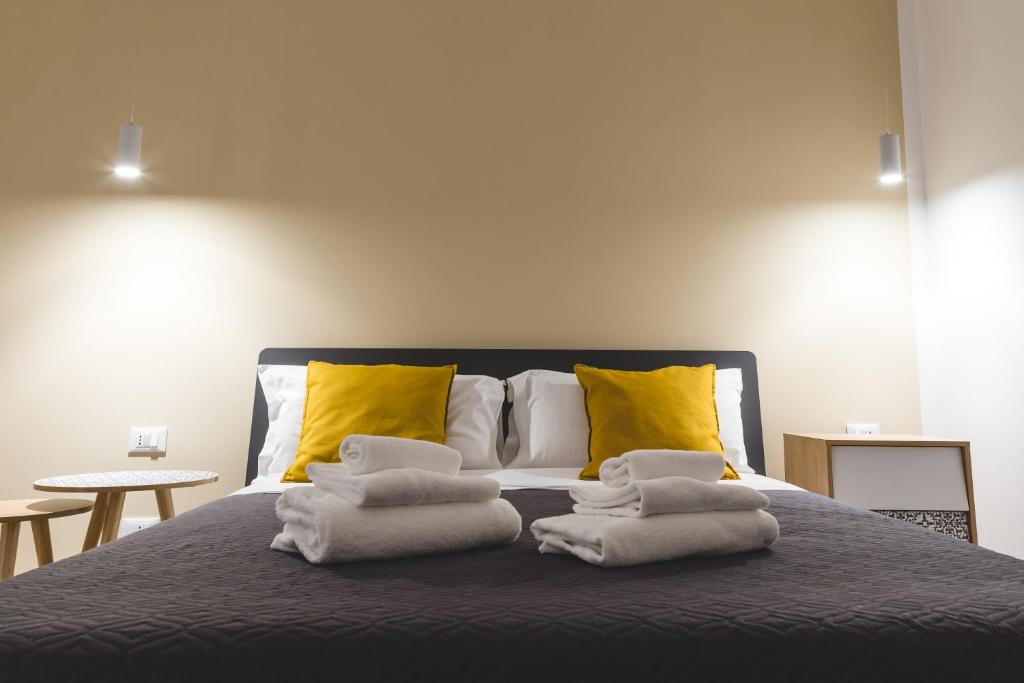 Una cama con toallas y almohadas amarillas. en La Meridiana, en Castellammare del Golfo