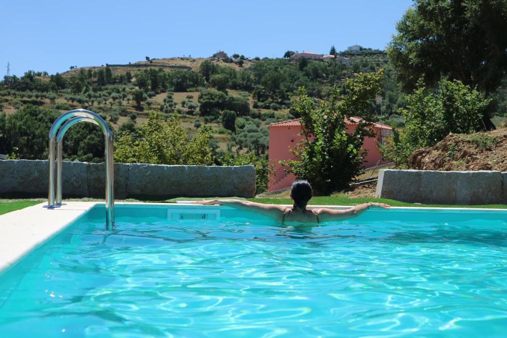 un hombre en una piscina con vistas a una montaña en Quinta da Retorta, en Pinhel