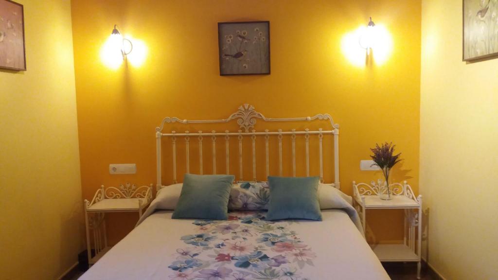 een slaapkamer met een bed met blauwe kussens en 2 tafels bij Alameda II con CHIMENEA Salòn y BARBACOA en patio in Curiel de Duero