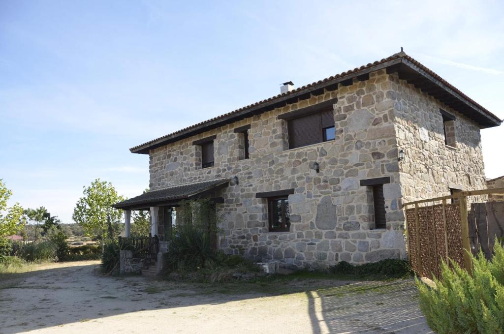 Luelmo的住宿－Casa Rural Alada，一座古老的石头房子,前面有栅栏