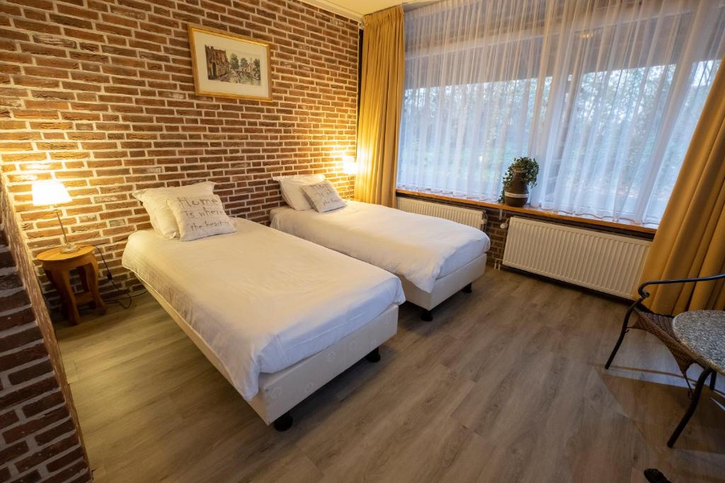 Cette chambre comprend 2 lits et un mur en briques. dans l'établissement Buitengoed de Panoven, à Zevenaar