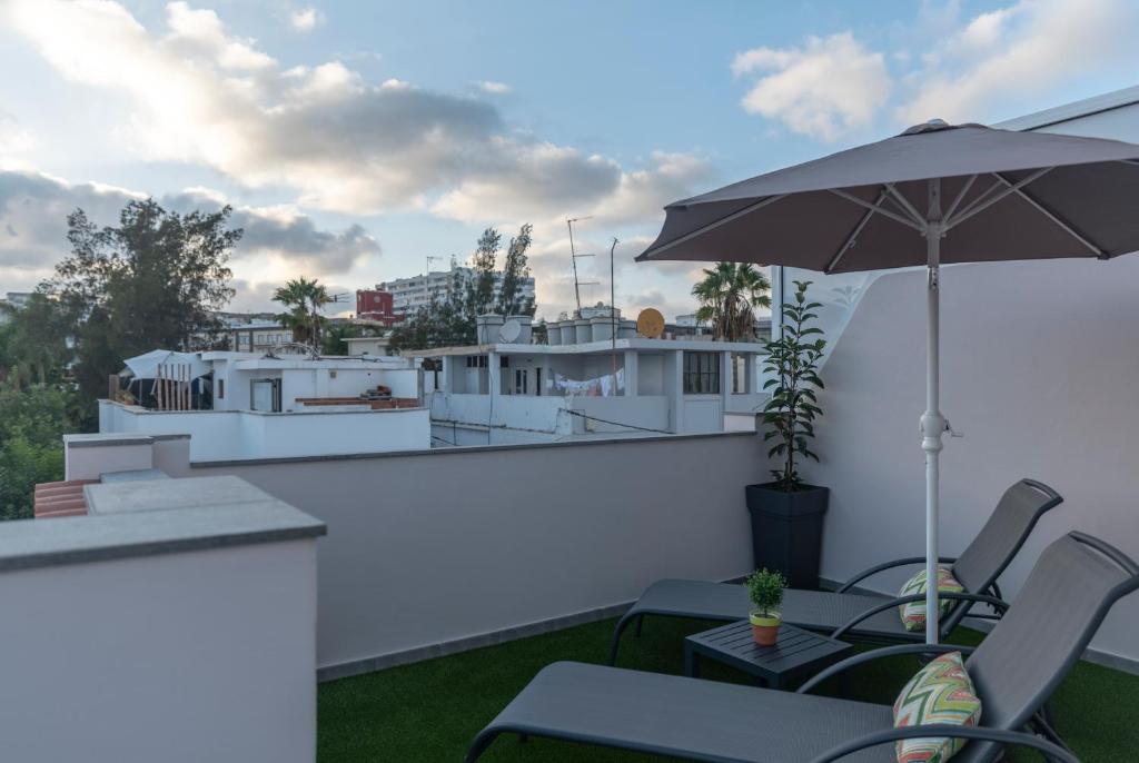een patio met stoelen en een parasol op een balkon bij La Palmera Hotel Boutique in Las Palmas de Gran Canaria
