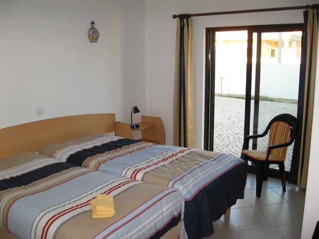 a bedroom with a bed and a chair and a window at Esti Chamaco - Lagos in Lagos