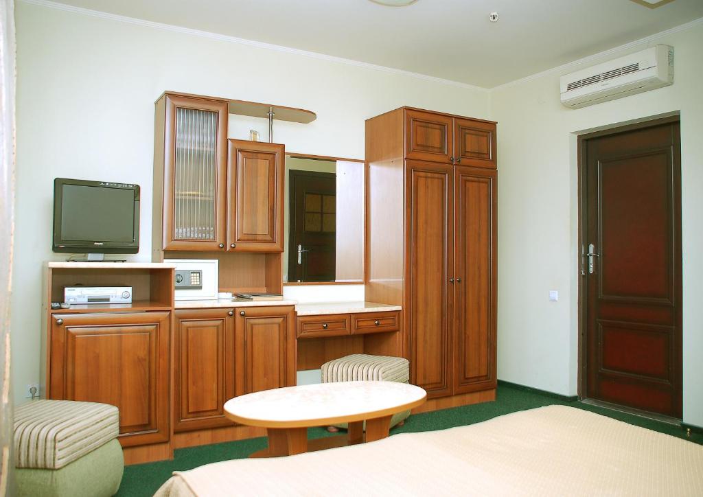 Habitación con armarios de madera, TV y mesa. en Prestige, en Leópolis