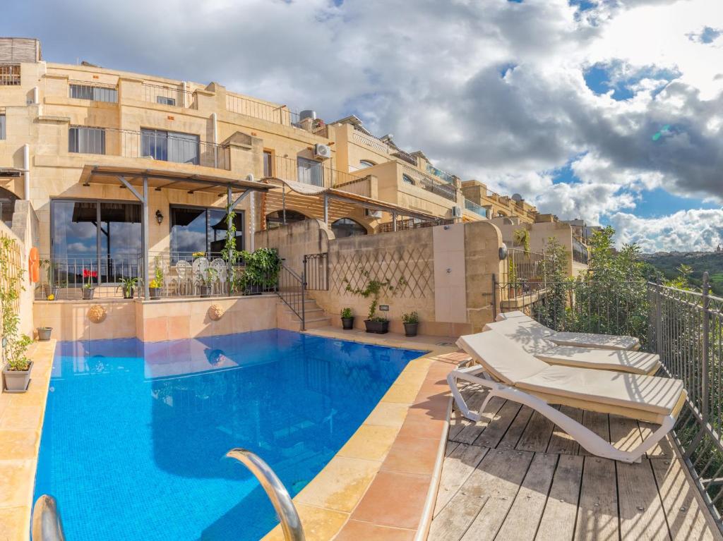 a apartment with a swimming pool in front of a building at Ghajn Damma in Xagħra