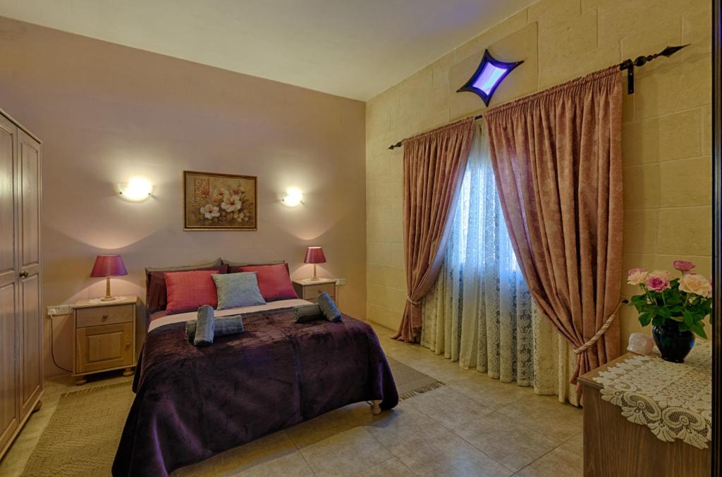 a bedroom with a bed and a window at Ghajn Damma in Xagħra