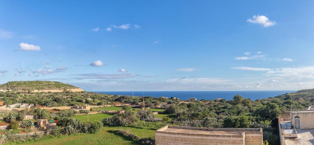 a view of a town with the ocean in the background at Ghajn Damma in Xagħra