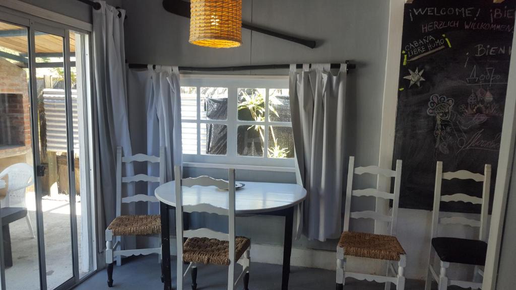 a dining room with a table and chairs and a window at Lunas del Bosque Cabaña y apartamento en suite in La Paloma