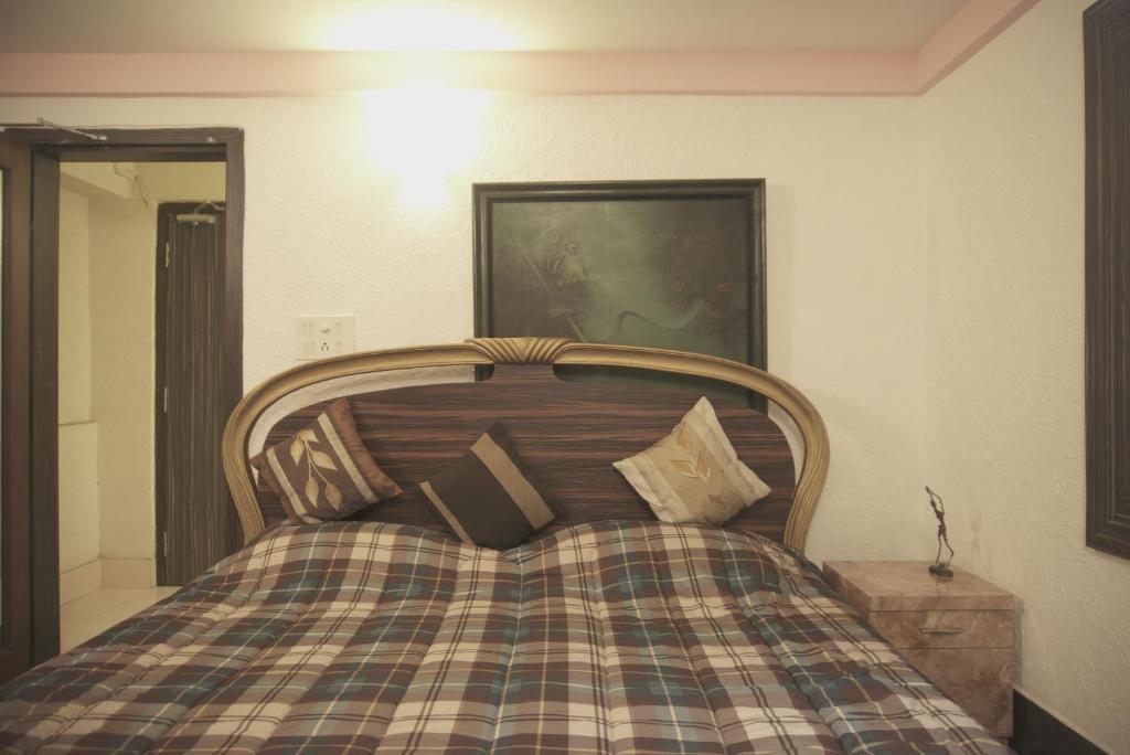 a bedroom with a bed with a plaid blanket at Reena's Lodge in Kolkata