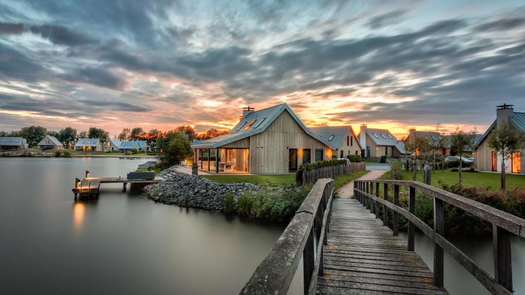 a house on a lake with a wooden bridge at Waterrijk Oesterdam Resort Villas in Tholen