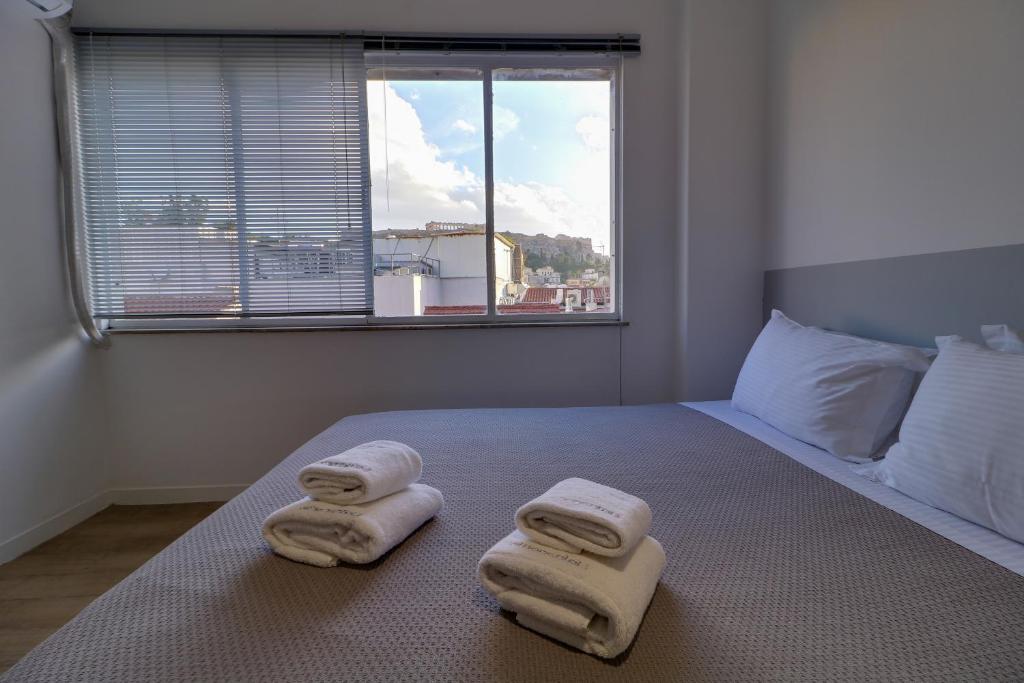 a bedroom with towels on a bed with a window at apartotel.acropolis.view in Athens