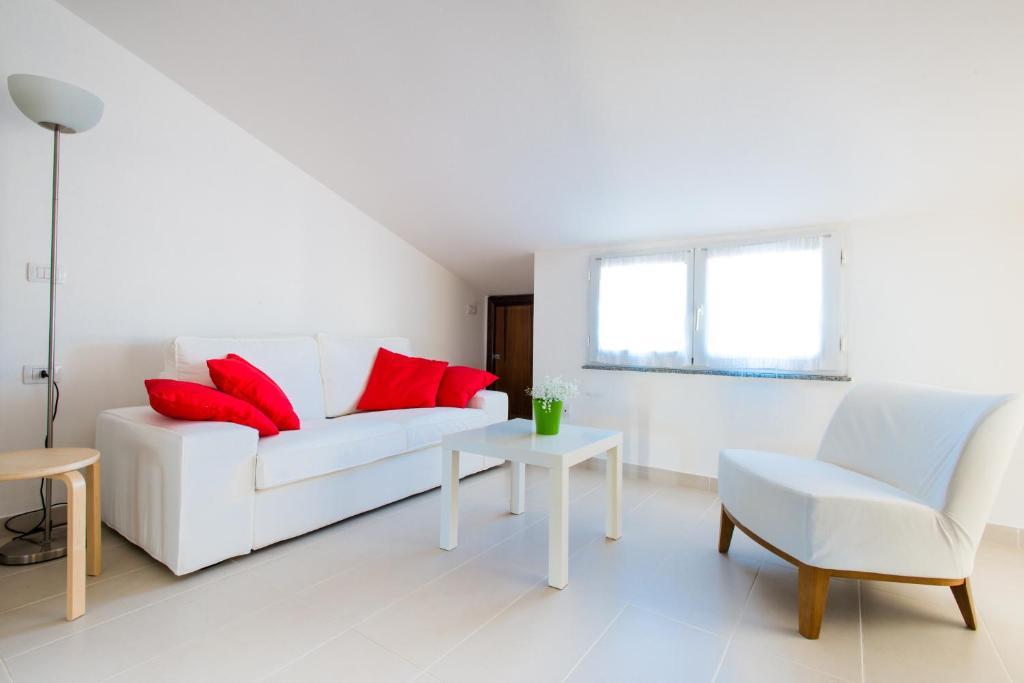 a living room with a white couch and red pillows at Sa Cruxitta Apartments in Portoscuso