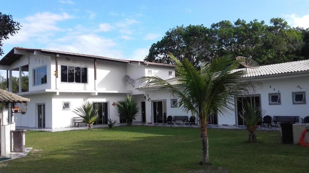 une maison blanche avec un palmier dans la cour dans l'établissement Pousada Camping e Pesca Bom Abrigo, à Cananéia