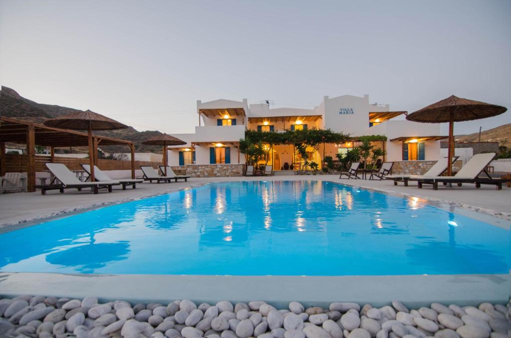 a large swimming pool with chairs and umbrellas at Villa Maria in Ios Chora