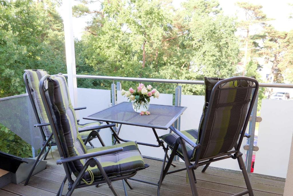 a table with chairs and a vase of flowers on a porch at Baabe Ferienwohnung 21 Kajuete Ref in Baabe