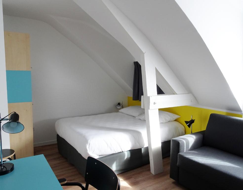 レンヌにあるRésidence Little Sévignéのベッド1台、椅子、ソファが備わる客室です。