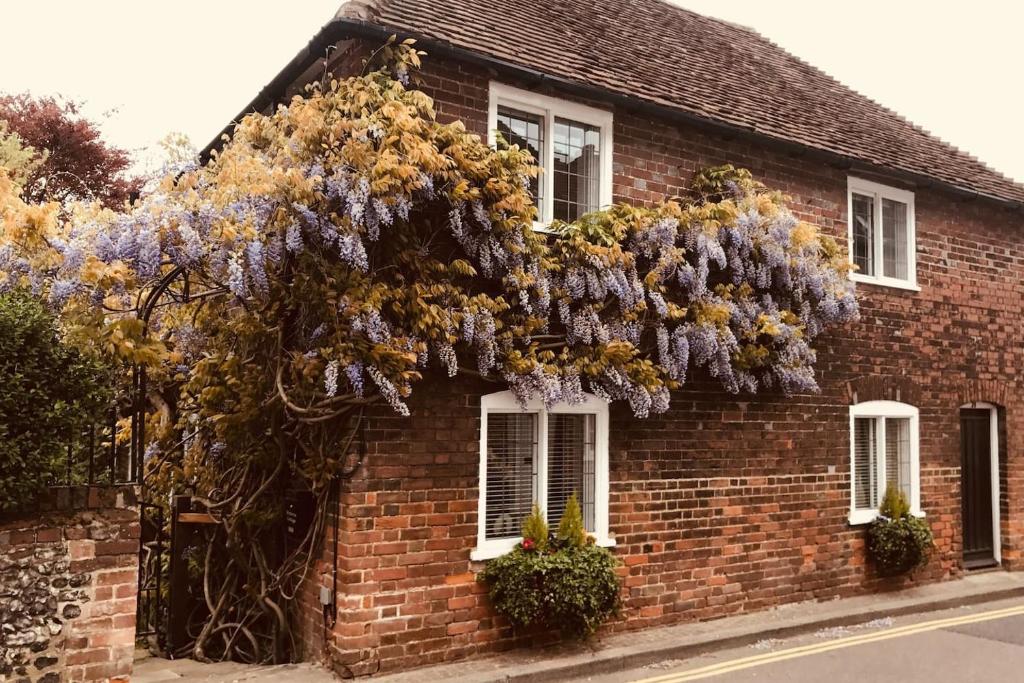 een stenen huis met een krans van bloemen erop bij Wisteria Cottage in Gravesend