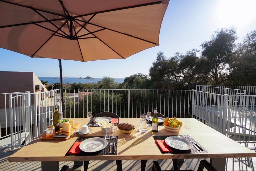 a wooden table with an umbrella on a patio at Casa Selvaggio Blu in Santa Maria Navarrese