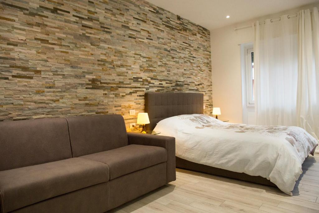 um quarto com uma cama, um sofá e uma parede de tijolos em San Pietro Dreaming Rooms em Roma