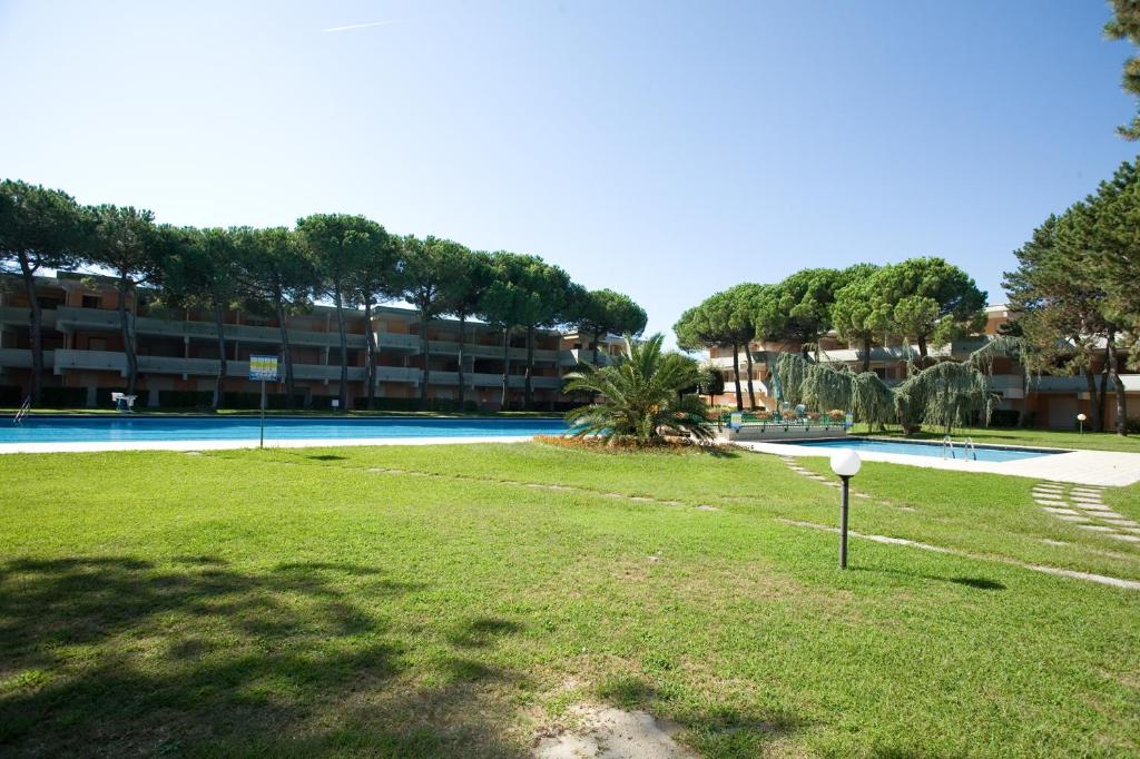 a swimming pool in a resort with a grass field at Solarium/piscina in Bibione