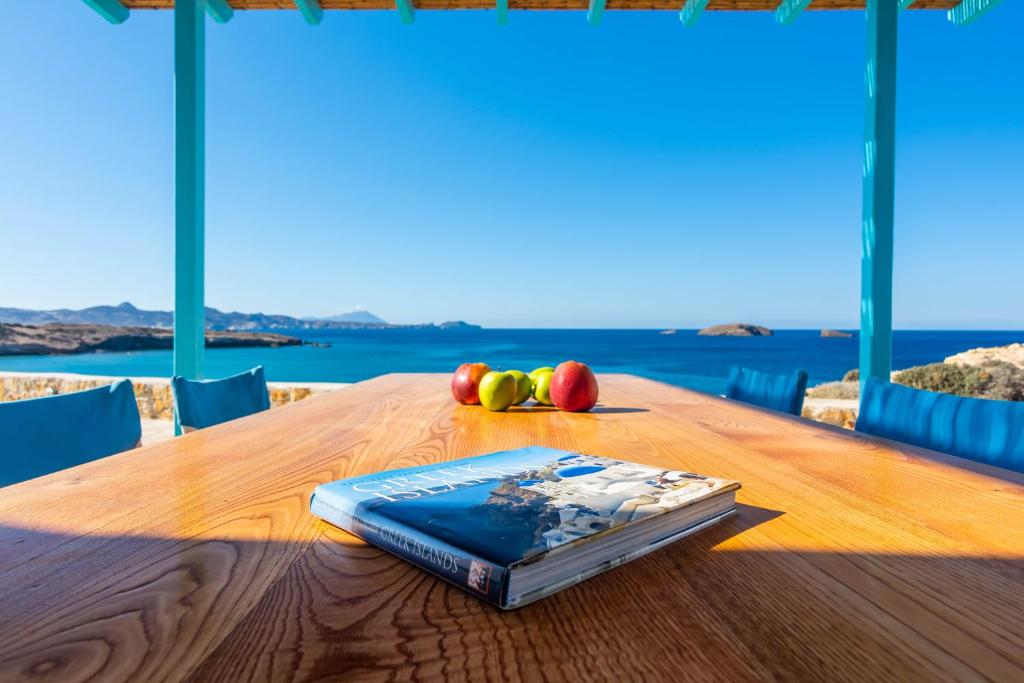 a book on a wooden table with fruit on it at Villa Zefyros in Pachaina