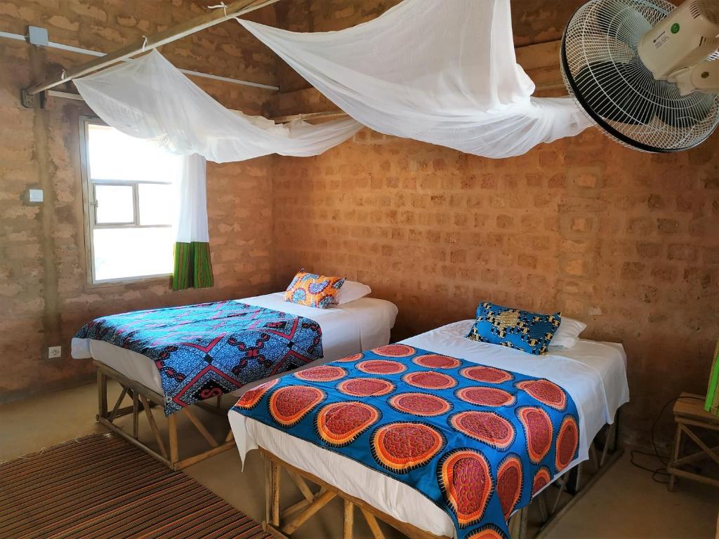 a room with two beds and a fan at Nguel du Saloum - Chez Abdou et Mar in Mar Lodj