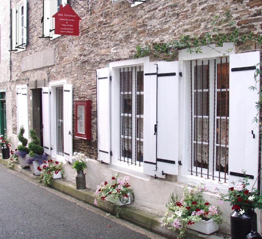 a building with white doors and flowers on a street at Chez Providence Chambres et Table d'Hôtes in Cuxac-Cabardès