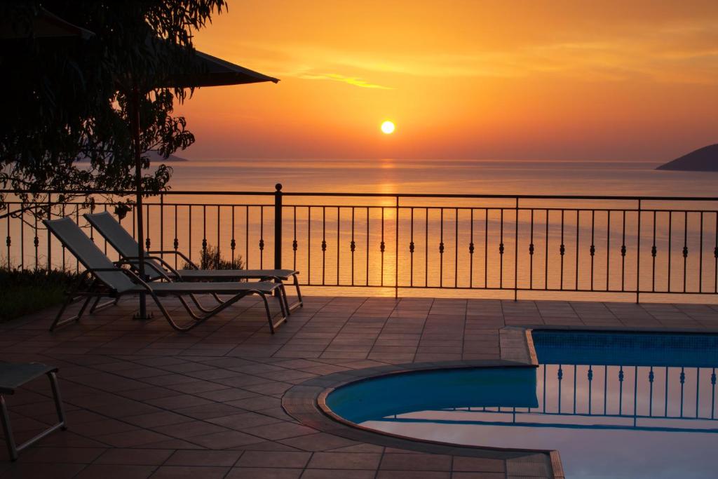 a sunset over the ocean with a chair and a pool at Fotini in Agia Effimia