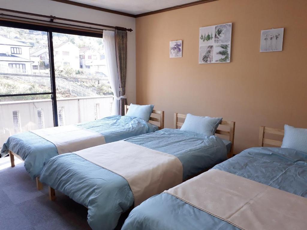 3 łóżka w pokoju z dużym oknem w obiekcie Gairoju / Vacation STAY 2366 w mieście Higashi-osaka